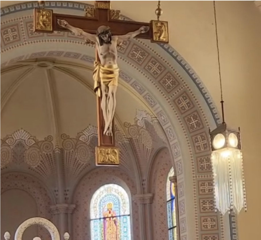 Crucifixo de madeira com vitral ao fundo, dentro da Igreja São José